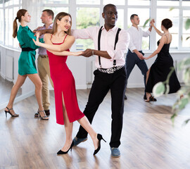 With unhurried music, woman with African man in couple spins to rhythm of waltz during lesson for...