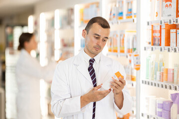 Man pharmacist holds out cream, remedy for solving skin problems, eliminating defects, review with...