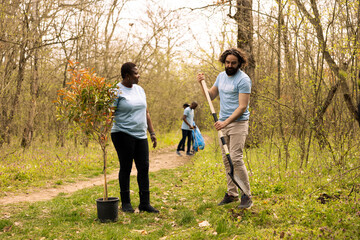 Team of diverse activists doing voluntary work to plant trees in the woods, protecting natural forest environment. Planting seedings for future generations, giving life and helping the planet.