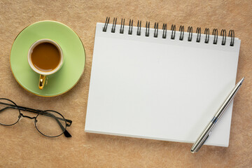 blank spiral notebook, flat lay with coffee and reading galsses on textured art paper