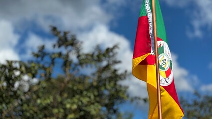 Flag of the State of Rio Grande do Sul waving in the wind on a nature background. Gaucho Flag. Week...