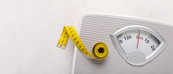 Scales with yellow measuring tape on white background