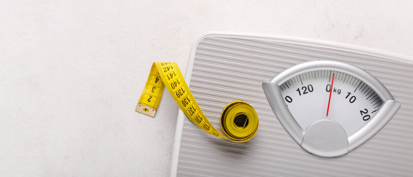 Scales with yellow measuring tape on white background