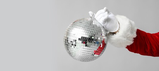 Hand of Santa Claus with disco ball on grey background with space for text