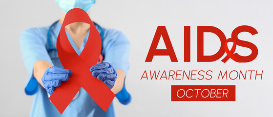 Female doctor with pink ribbon on light background, closeup. Breast cancer awareness concept
