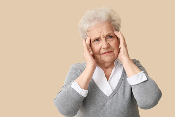 Stressed senior woman on beige background