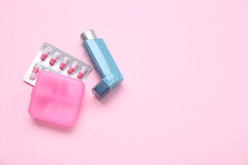 Asthma inhaler and box with pills on pink background