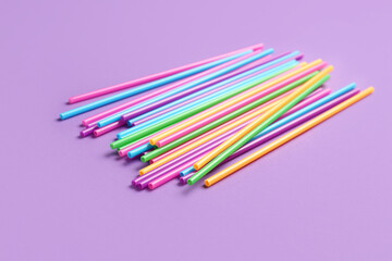 Different plastic straws on purple background