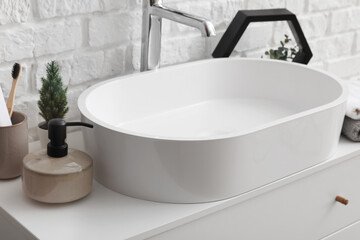 Sink bowl and bath accessories on table in bathroom, closeup