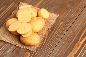 Raw baby potatoes and slices on wooden background