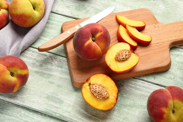 Board with cut sweet peaches on green wooden background