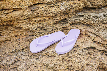 Stylish lilac flip-flops on rock