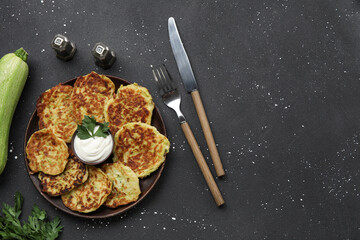 Plate with tasty zucchini fritters on grunge background