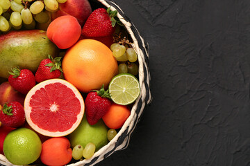 Bowl with different fresh fruits on black background