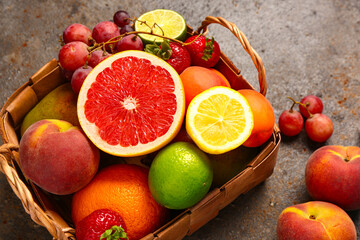 Wicker basket with different fresh fruits on dark table