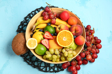 Bowl with different fresh fruits on blue background