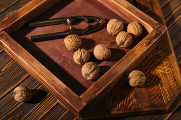 Different cutting boards with walnuts and nutcracker on wooden background
