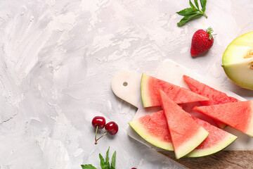 Board with pieces of fresh watermelon and different berries on white background