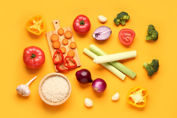 Bowl with rice and different fresh vegetables on orange background