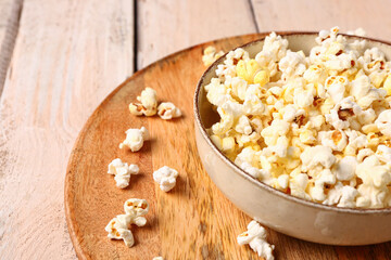 Bowl with tasty popcorn on white wooden background