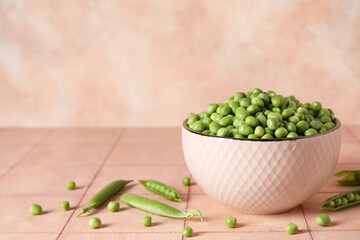Bowl with fresh green peas on pink tile table