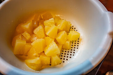 Tinned pineapple chunks draining in a plastic colander.