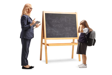 Full length profile shot of a teacher talking to a sad schoolgirl in front of blackboard