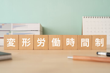 変形労働時間制の文字が入ったブロックが置かれたデスク