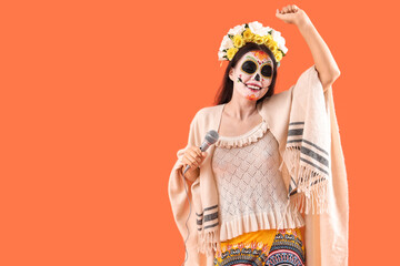 Beautiful woman dressed for Halloween with microphone dancing on orange background