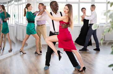 Pair of woman and African American man enjoying of sensual tango dance in choreo class. Exciting...