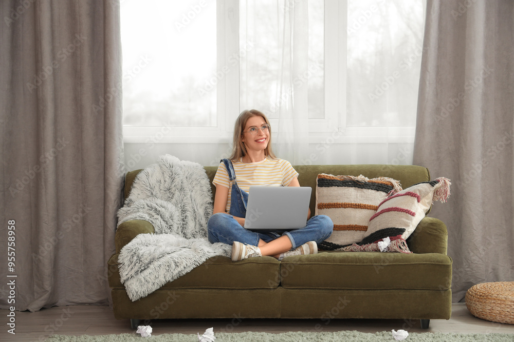 Poster female author using laptop on sofa at home