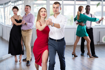 Obraz premium Dance studio - a group of beautifully dressed people learn to dance tango