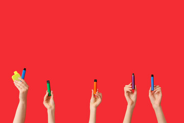 Many hands holding electronic cigarettes on red background