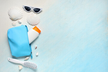 Cosmetic bag with text MAKE UP, seashells and sunscreen on blue background