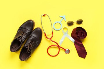 Shoes, stethoscope, tie, male sign and light blue ribbon on yellow background. Prostate cancer awareness