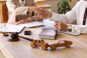 Wooden cars on lawyer's table during meeting in office, closeup