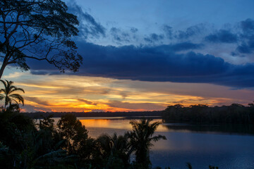 Naklejka premium Beautiful sunset over a calm lake with tree silhouettes