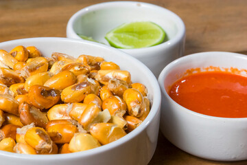 Close-up of roasted corn kernels with lime and sauce.