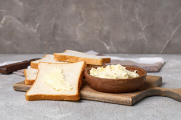 Wooden board with fresh butter and toasts on grunge table