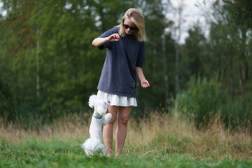 Girl is playing with the dog in the park forest. Rest concept. Woman walking with a dog on a leash during a good day