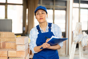 Woman foreman checks the completed construction work on the drawing