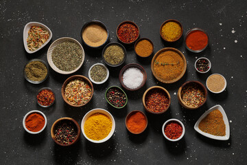 Composition with many different bowls of fresh spices on dark background