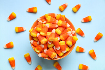 Bowl of tasty Halloween candy corns on color background