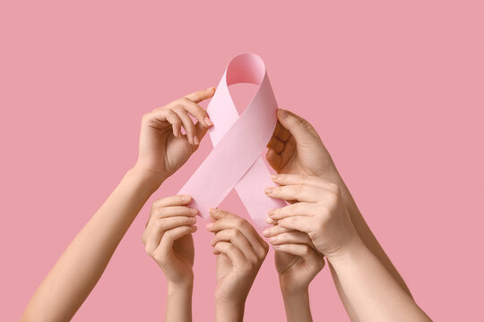 Many female hands with pink ribbon on color background. Breast cancer awareness concept