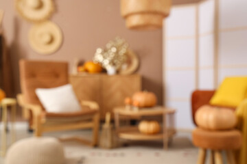 Blurred view of living room with armchair, table and autumn decor