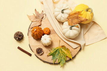 Composition with autumn candles, ripe pumpkins and fallen leaves on color background
