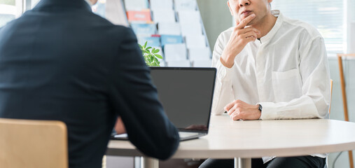 保険の相談に来た中年男性と接客対応する男性ビジネスマン
