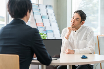 保険の相談に来た中年男性と接客対応する男性ビジネスマン
