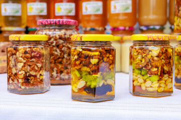 A table with several jars of nuts and fruit, walnuts in honey