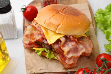 Delicious burger with bacon served on white table